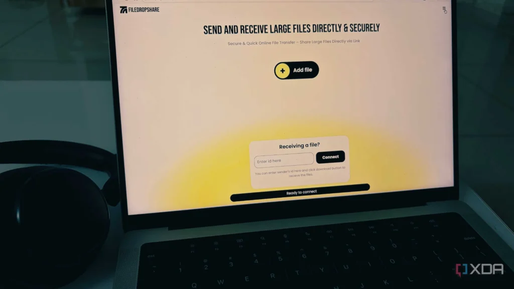 A laptop screen displays a file transfer interface, featuring options to send and receive large files securely, with a headset nearby.