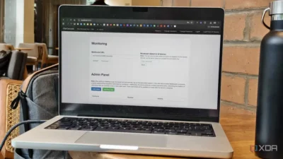 A laptop displays an admin panel with monitoring options, set in a modern café environment with a water bottle beside it.