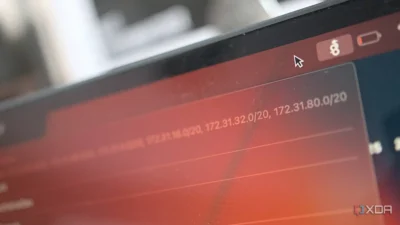 A close-up of a computer screen displaying network IP addresses with a red background, cursor in view, and battery indicator at the top.