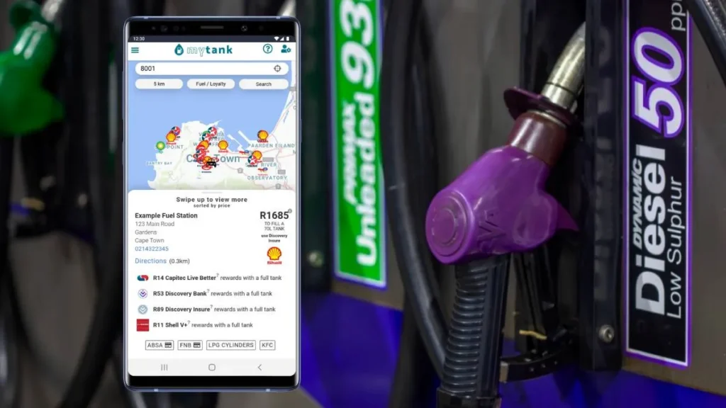 Smartphone displaying fuel price and station app next to a purple diesel fuel nozzle at a gas pump.