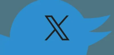 Blue Twitter bird logo with a black stylized "X" symbol overlaying the center on a gray background.