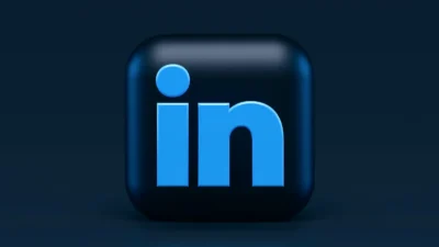 LinkedIn logo in blue on a dark rounded square background, centered on a dark gradient backdrop.