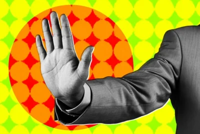 Black and white hand raised in a stop gesture against a vibrant geometric background with red, orange, yellow, and green colors.