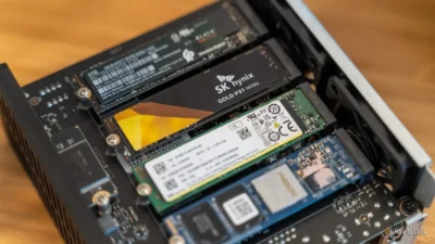 Close-up of multiple NVMe SSDs installed on a computer motherboard inside a case on a wooden surface.