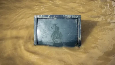 Old television partially submerged in muddy floodwater with a faint reflection of a person and electrical wires.
