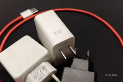 Three smartphone chargers with different plugs and a red USB cable on a black surface.