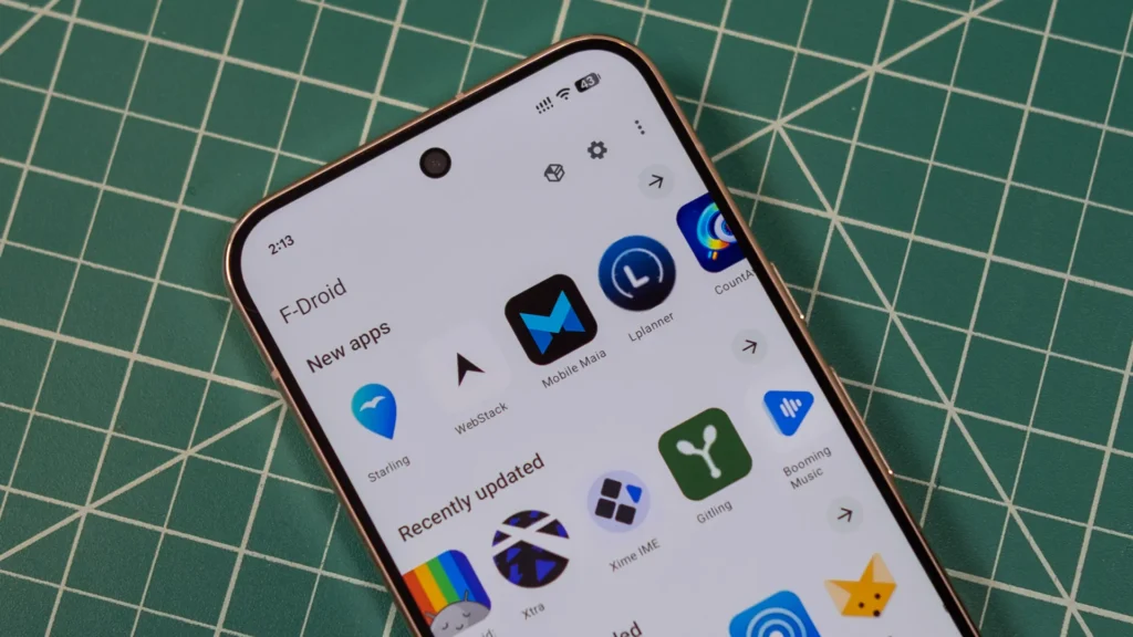 Smartphone displaying the F-Droid app store on a green cutting mat, with various app icons visible.