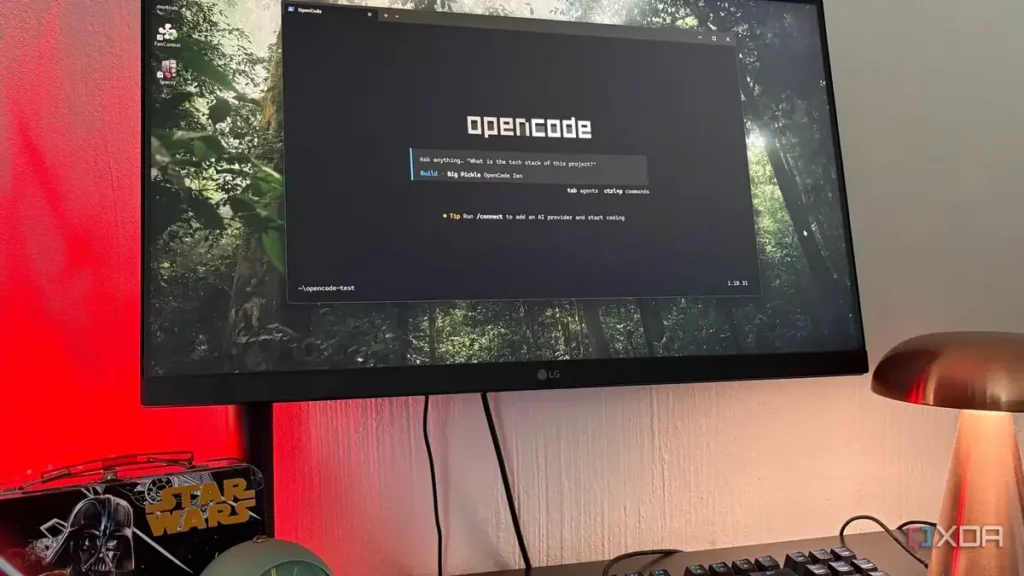Computer monitor displaying OpenCode interface, with Star Wars lunchbox, mechanical keyboard, and copper desk lamp on a desk.
