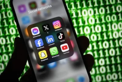Australians Could Soon Opt Out of Social Media Algorithms Altogether 3 Smartphone screen displaying a folder labeled "Social networks" with popular social media app icons, against a background of green binary code.
